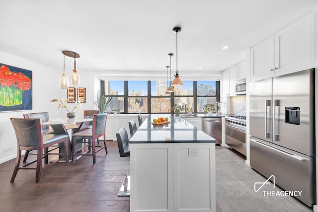 kitchen featuring a kitchen island, premium appliances, a sink, white cabinets, and tasteful backsplash