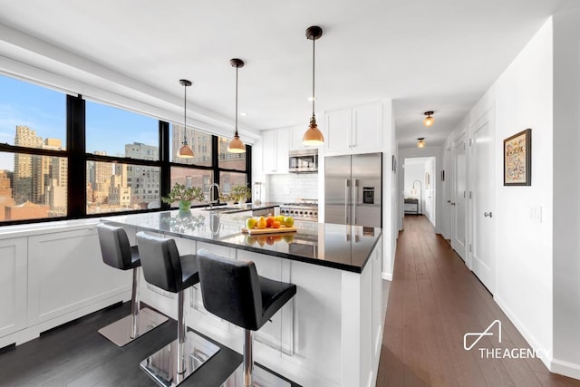 kitchen featuring white cabinets, stainless steel appliances, a city view, pendant lighting, and a sink