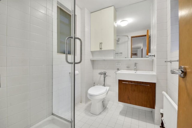 bathroom featuring a shower with door, vanity, tile walls, and toilet