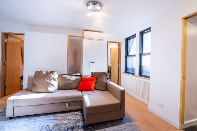 living area featuring an AC wall unit, baseboards, and light wood finished floors