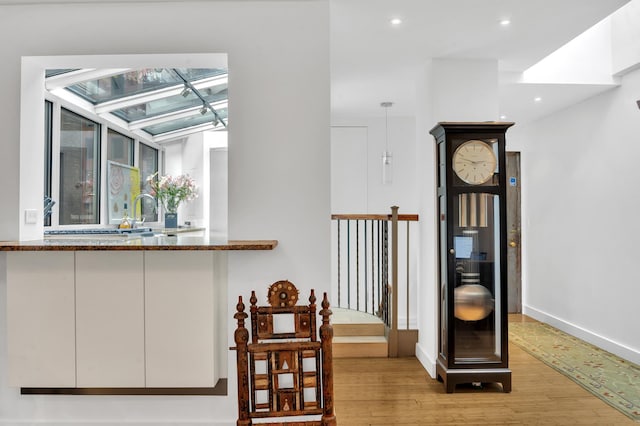 hallway with recessed lighting, a sink, light wood-style flooring, and baseboards