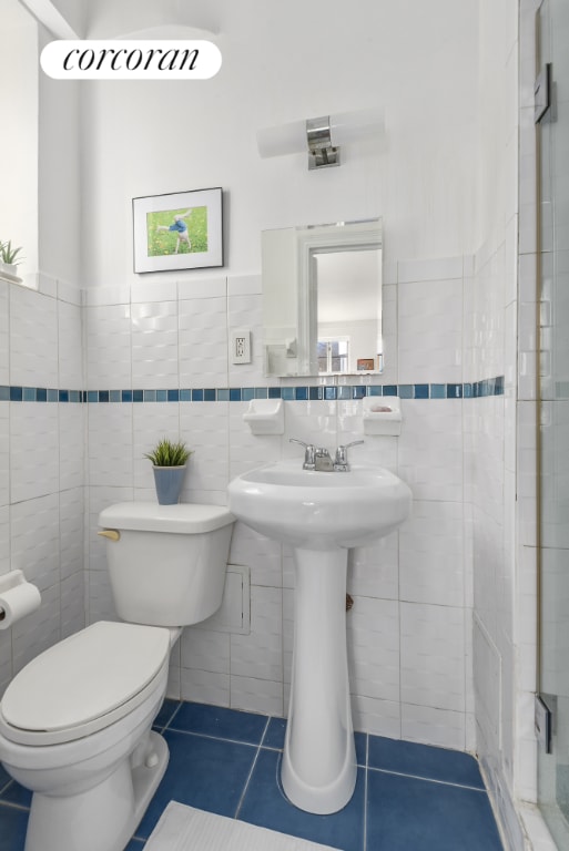 bathroom featuring tile walls, tile patterned floors, and toilet