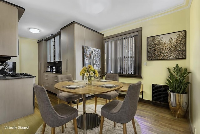 dining space with light wood-style floors, crown molding, and baseboards