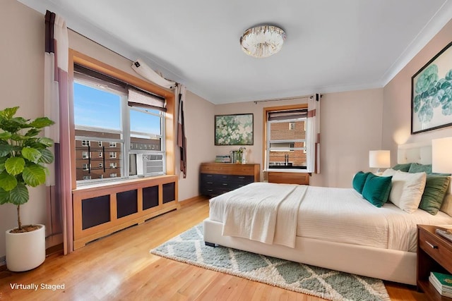 bedroom featuring multiple windows, crown molding, and wood finished floors