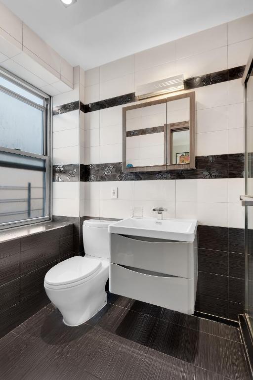 bathroom featuring toilet, vanity, and tile walls