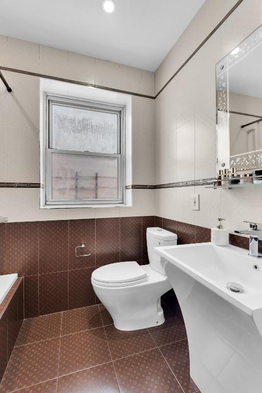 full bath featuring tile patterned flooring, tile walls, and toilet