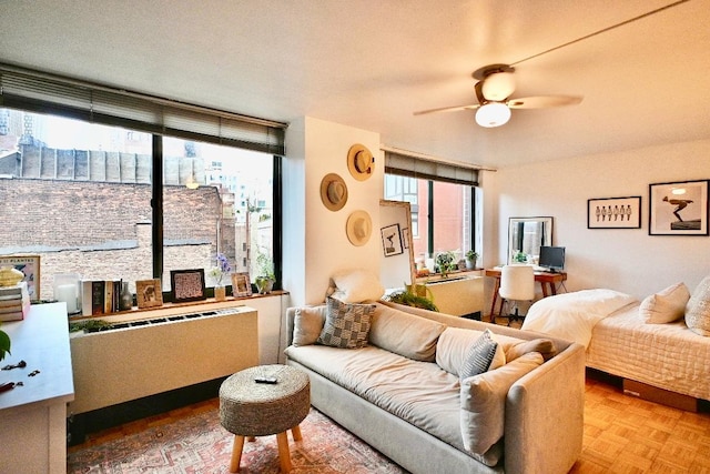 living room featuring parquet floors, a wealth of natural light, radiator, and ceiling fan