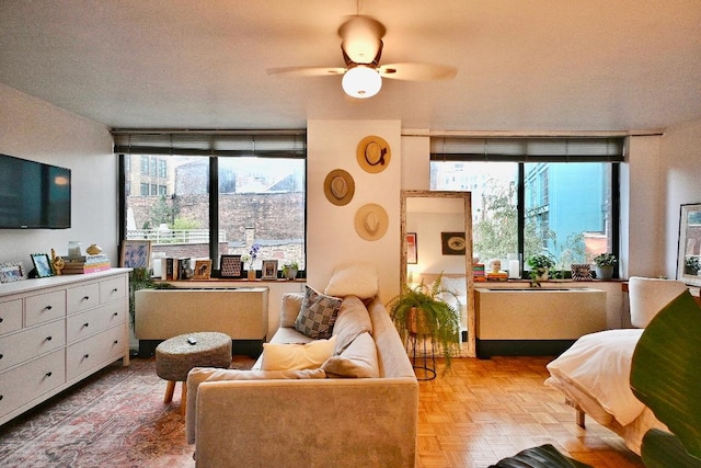 living room with ceiling fan, light parquet flooring, and a textured ceiling