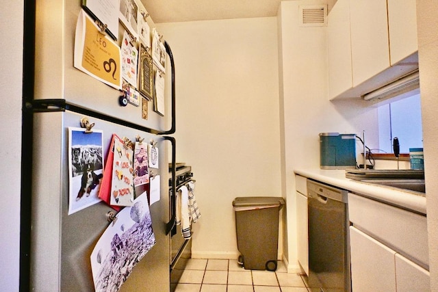 kitchen featuring sink, white cabinetry, refrigerator, light tile patterned floors, and black dishwasher