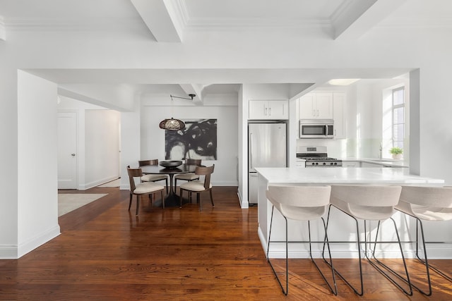 kitchen with dark wood-style floors, a breakfast bar, a peninsula, stainless steel appliances, and light countertops