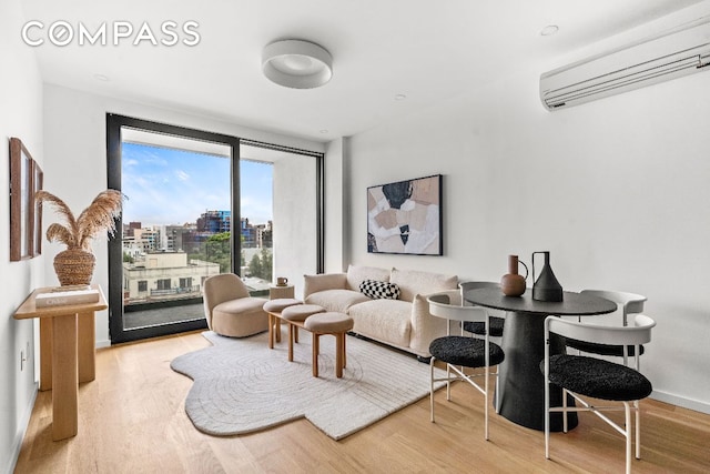 living area featuring baseboards, wood finished floors, a city view, and a wall mounted air conditioner