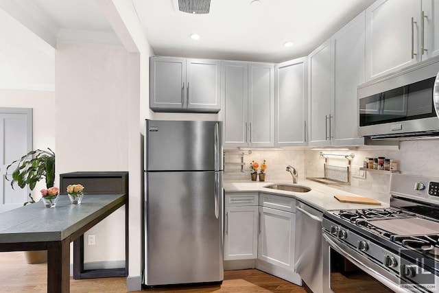 kitchen featuring stainless steel appliances, tasteful backsplash, light countertops, visible vents, and a sink