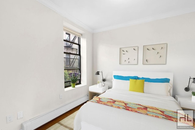 bedroom featuring a baseboard heating unit, wood finished floors, and crown molding