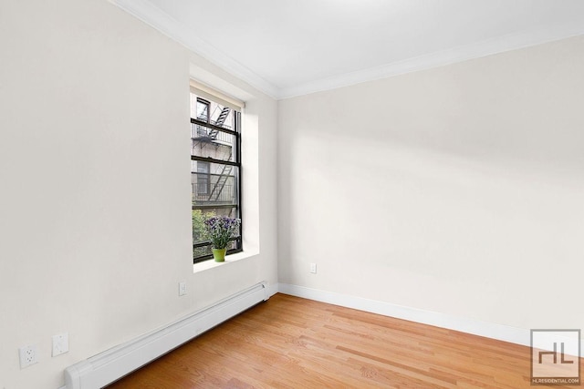 spare room featuring light wood-style flooring, ornamental molding, baseboard heating, and baseboards