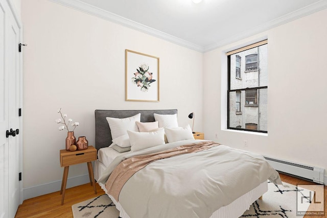 bedroom featuring a baseboard radiator, crown molding, baseboards, and wood finished floors