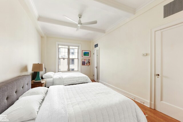 bedroom featuring hardwood / wood-style flooring, ornamental molding, ceiling fan, and beam ceiling