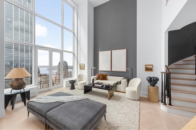 living area featuring baseboards, stairway, and a high ceiling