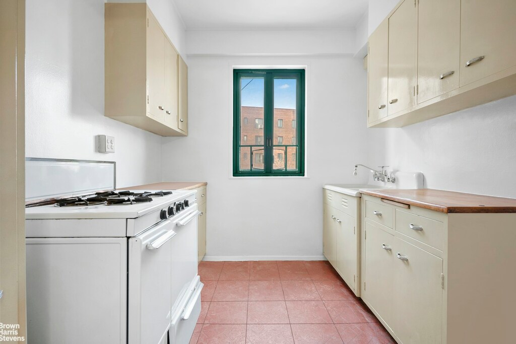 kitchen featuring cream cabinets, sink, white gas range oven, and light tile patterned floors