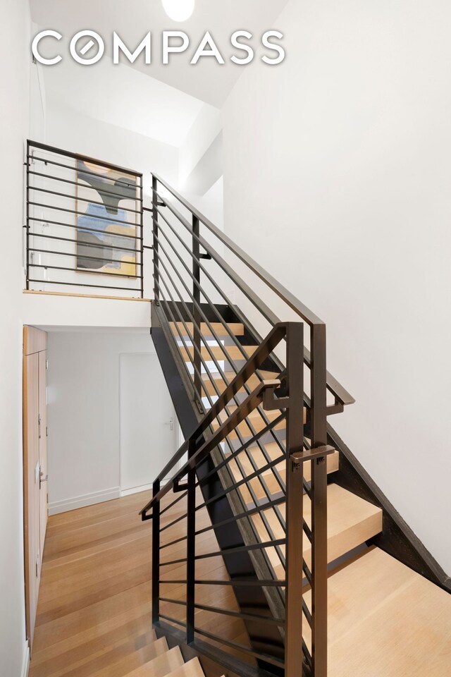 stairway with a high ceiling and wood-type flooring