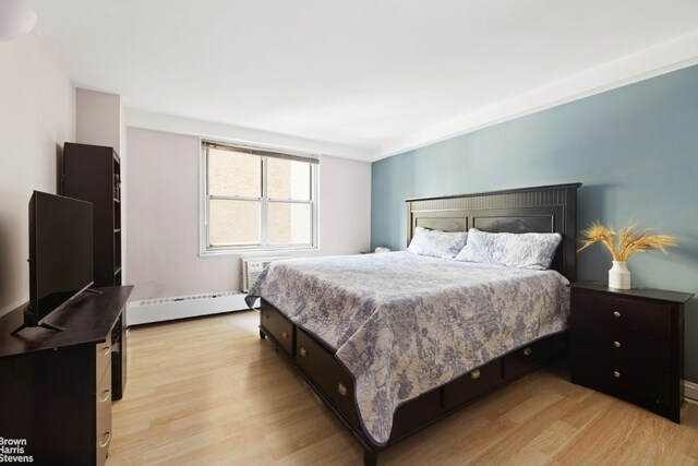 bedroom with light hardwood / wood-style flooring and a baseboard heating unit