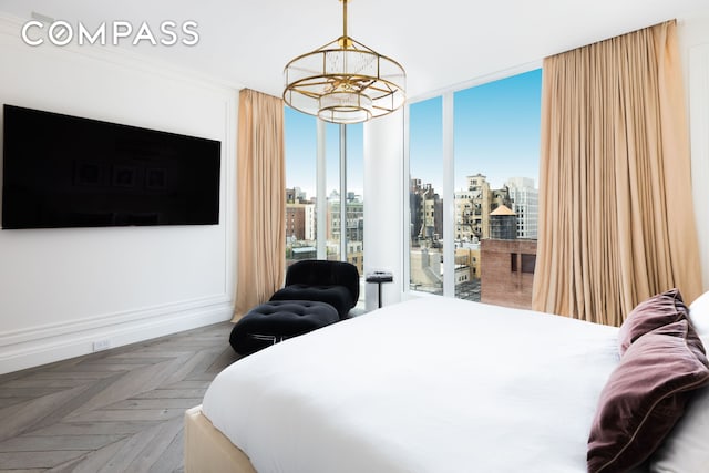 bedroom featuring a city view, crown molding, a notable chandelier, access to outside, and baseboards