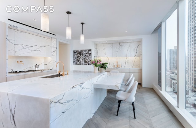 kitchen with light stone countertops, decorative backsplash, a sink, gas cooktop, and modern cabinets
