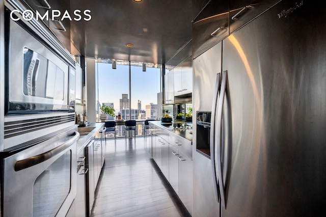 kitchen featuring a city view, modern cabinets, floor to ceiling windows, stainless steel appliances, and white cabinets