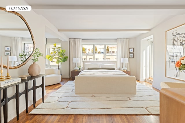 bedroom with beamed ceiling, multiple windows, and hardwood / wood-style flooring