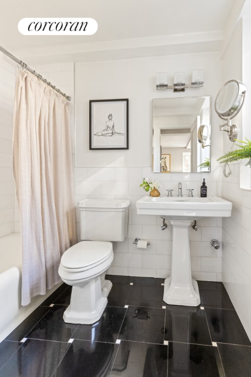 bathroom with tile walls, shower / tub combo, and toilet