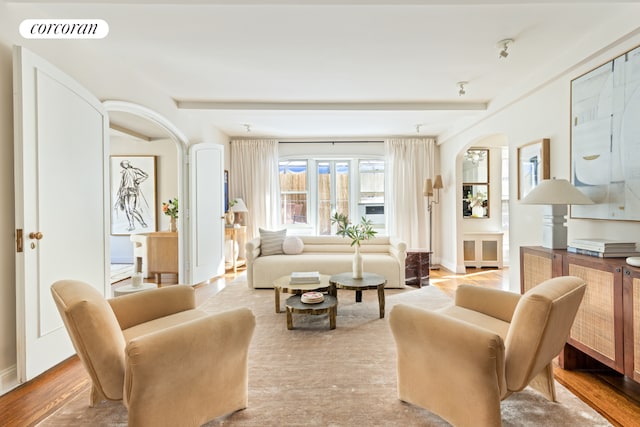 living area with beamed ceiling and light hardwood / wood-style flooring