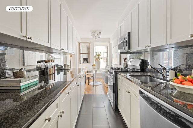 kitchen featuring sink, white cabinetry, dark stone countertops, appliances with stainless steel finishes, and decorative backsplash