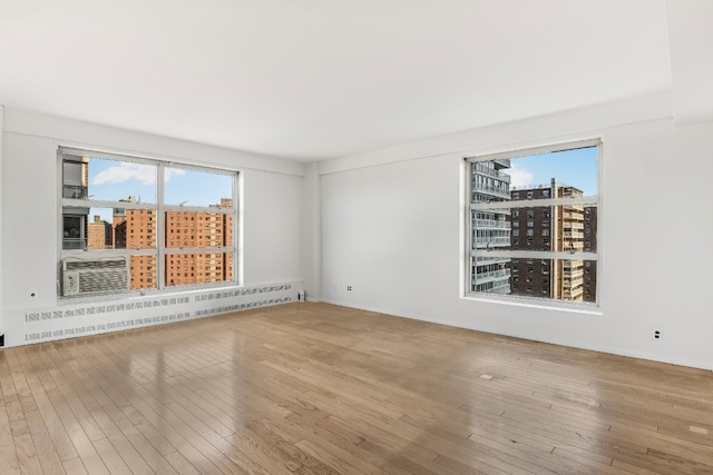 unfurnished room featuring baseboard heating and hardwood / wood-style flooring