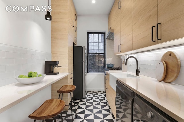 kitchen featuring stainless steel refrigerator, black dishwasher, sink, and backsplash