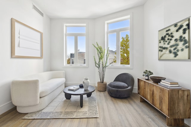 living area with light wood-type flooring, visible vents, and baseboards