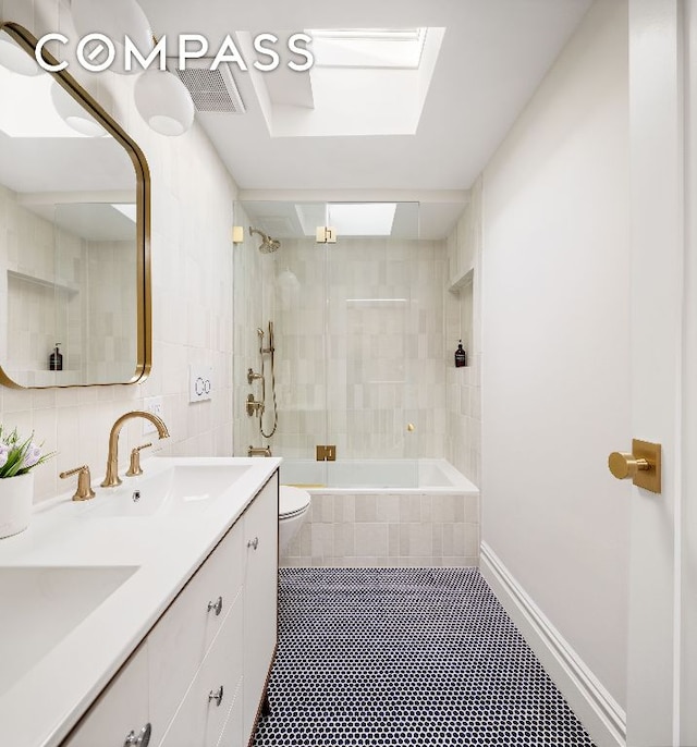 full bathroom featuring vanity, a skylight, toilet, and tiled shower / bath