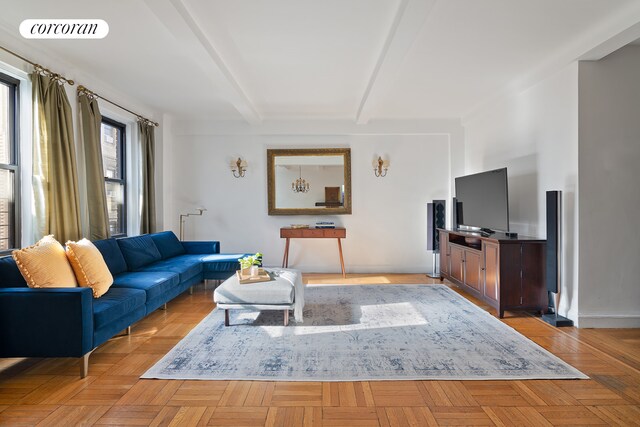 living room with beamed ceiling, a healthy amount of sunlight, radiator, and a notable chandelier