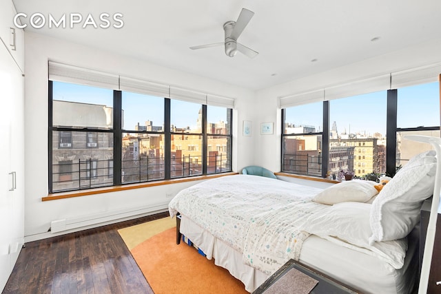 bedroom with a ceiling fan, a city view, and wood finished floors