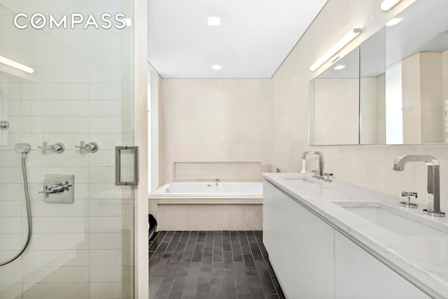 full bath with double vanity, a sink, a bath, and a stall shower