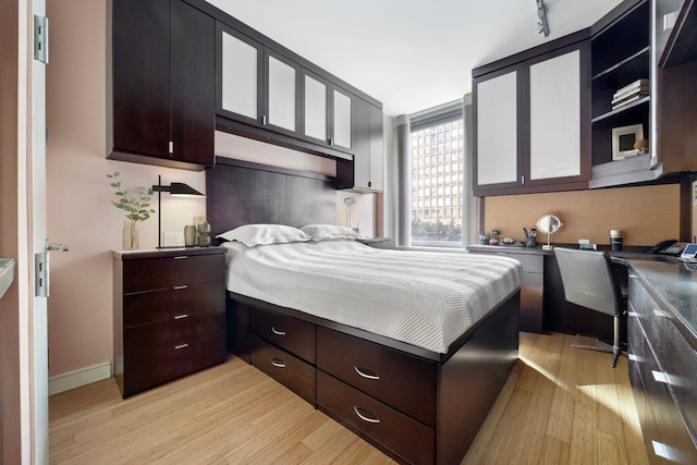 bedroom with baseboards, light wood-style floors, and built in study area