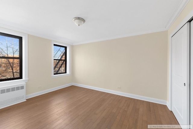 interior space featuring wood-type flooring, radiator, crown molding, and a closet