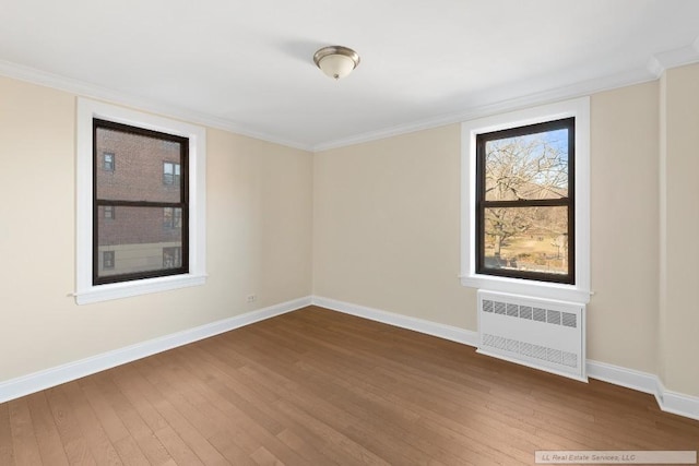 unfurnished room featuring hardwood / wood-style flooring, crown molding, and radiator