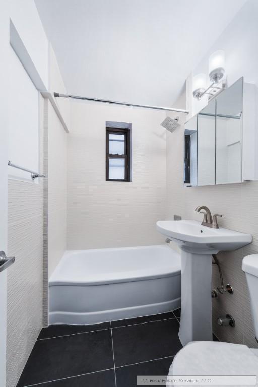 bathroom featuring tile patterned floors, toilet, and tiled shower / bath combo