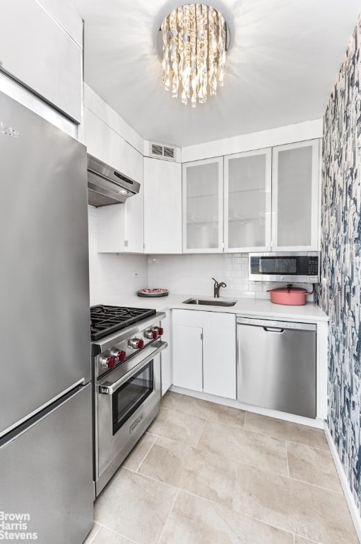 kitchen featuring white cabinetry, sink, backsplash, a notable chandelier, and stainless steel appliances