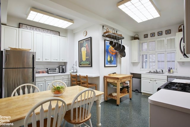 kitchen featuring light countertops, appliances with stainless steel finishes, a sink, and white cabinetry