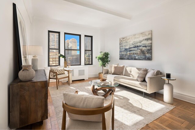 living room featuring parquet flooring, radiator heating unit, and beam ceiling