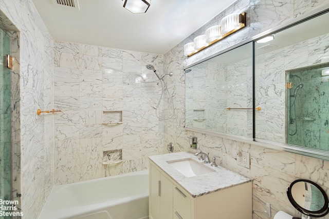 full bath featuring  shower combination, visible vents, tile walls, and vanity