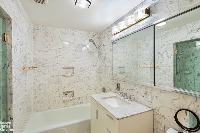 425 E 58th St Unit 8F, New York City, NY 10022 - bathroom with visible vents, vanity, shower / bathtub combination, and tile walls
