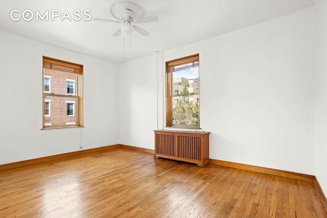 spare room featuring ceiling fan, radiator heating unit, and hardwood / wood-style floors