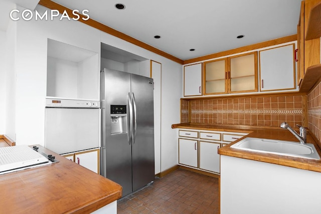 kitchen featuring tasteful backsplash, sink, stainless steel fridge, and white cabinets