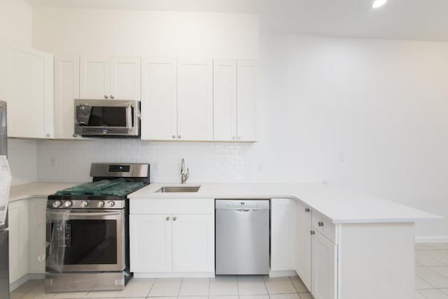 kitchen with stainless steel appliances, light countertops, a sink, and white cabinetry